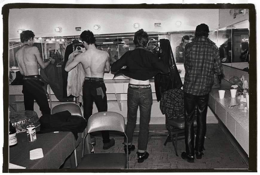 The Clash in a backstage dressing room with their backs to the camera. You can't see their faces, which will be revealed at another part of the page.