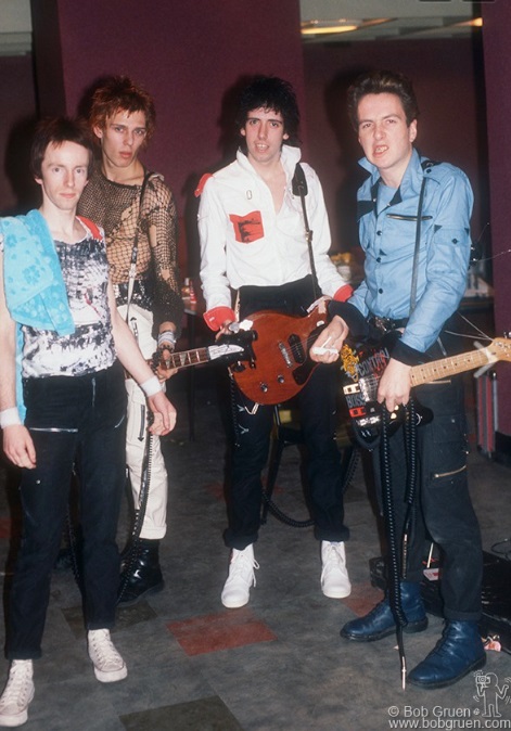 The Clash backstage at Leeds University Union, England. October 27, 1977. Photo by Bob Gruen. This photo shows well all four members in a color photo with their variety of fashion.