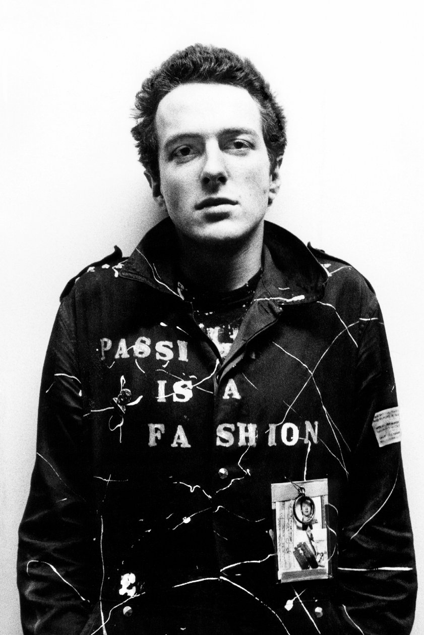 Joe looking at the camera in a black and white photograph with a biker jacket with the words 'Passion is a Fashion' stenciled across the chest.