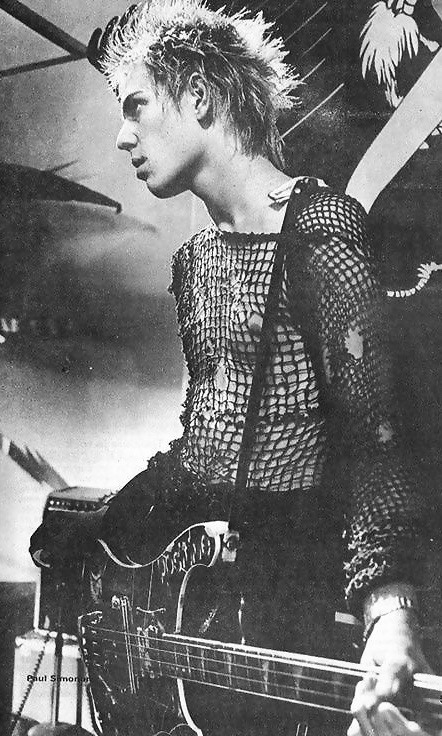 A black and white photograph of Paul playing bass on stage in his hand-knit DIY sweater.