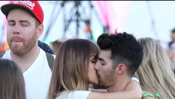 Man stands unamused as two other concert goers makeout in front of him