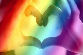 Two hands making a heart shape with a rainbow colored overlay.