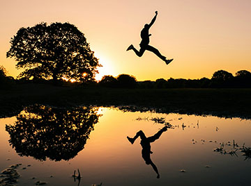 person jumping across a pond
