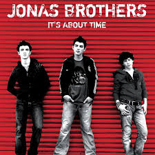 Black-and-red cover with three young men standing casually in front of a corrugated red wall, with Jonas Brothers and It's About Time in bold white text at the top.