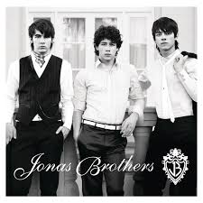 Black-and-white album cover of three young men in dressy outfits standing in front of a building, with Jonas Brothers written in cursive at the bottom corner.