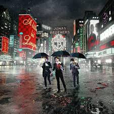 Album cover showing three men in suits walking in a rainy city street at night under black umbrellas, surrounded by bright billboards and neon signs.