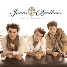 Soft-toned cover of three young men leaning on a table, looking at the camera, with Jonas Brothers written in elegant script above them.