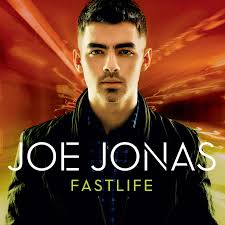 Album cover showing a close-up of a man in a dark jacket staring at the camera, with streaks of yellow and orange light blurring behind him and the text “Joe Jonas – Fastlife” across the bottom.