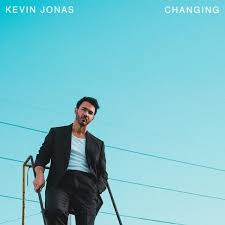 Single cover of a man in a dark suit jacket and white shirt standing on outdoor steps against a clear blue sky, with small text in the corners reading “Kevin Jonas” and “Changing.”