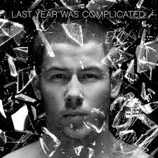 Black-and-white album cover featuring a close-up of a man’s serious face surrounded by flying shards of glass, with the title “Last Year Was Complicated” at the top.