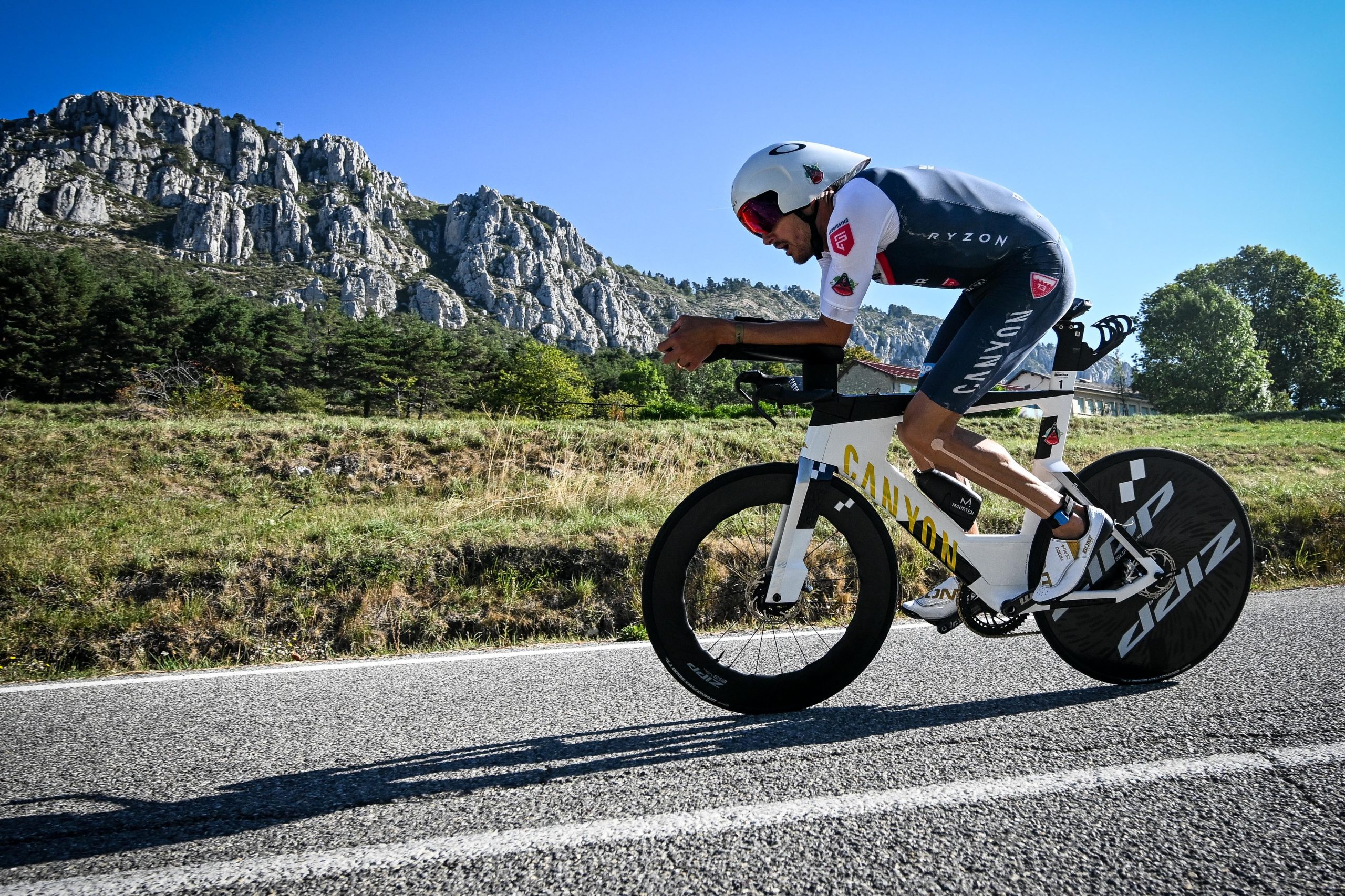 a man biking on a road with a mountain in the background