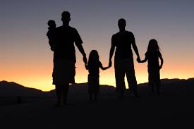 Picture of two parents holding their children's hands while looking at a sunset