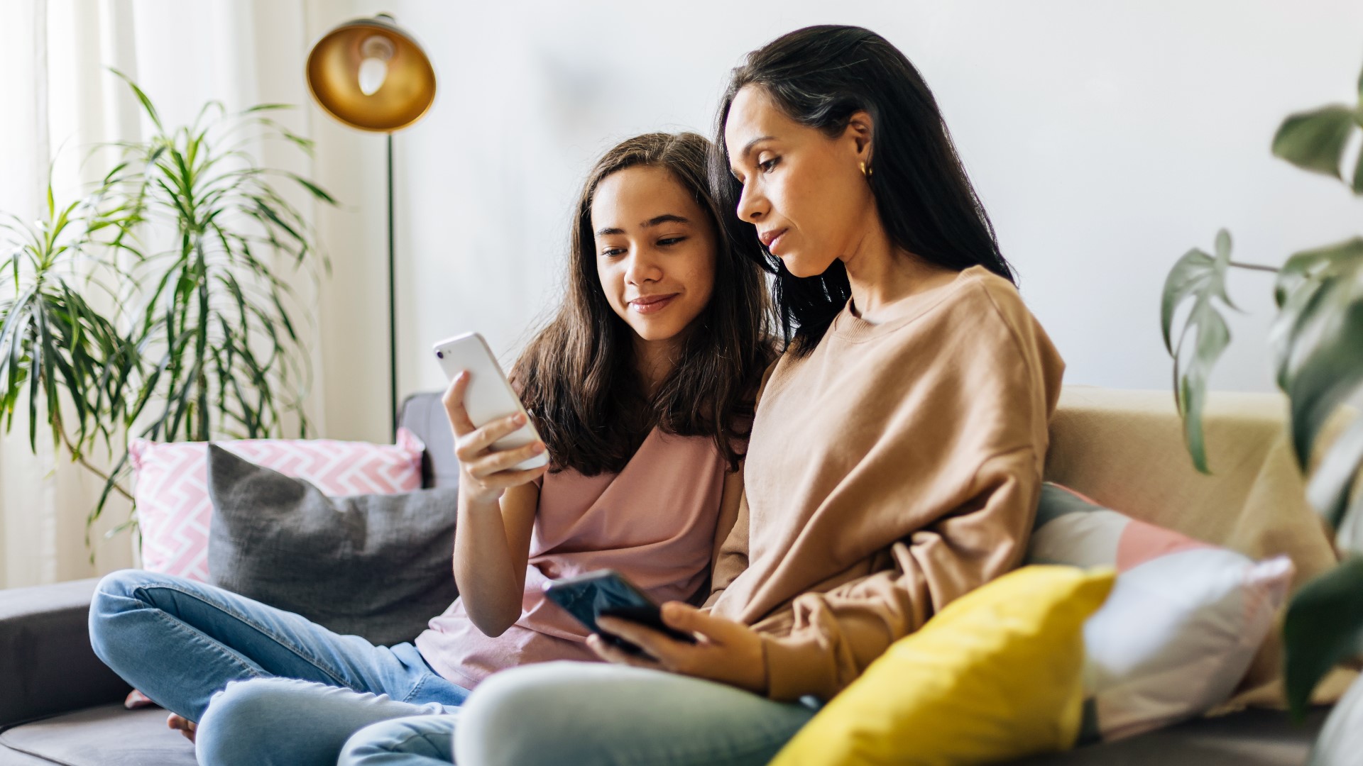 a happy girl showing her mother a photo on her phone.