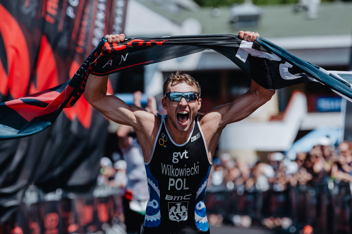 a man holding up the finish line ribbon as he celebrates winning an ironman race