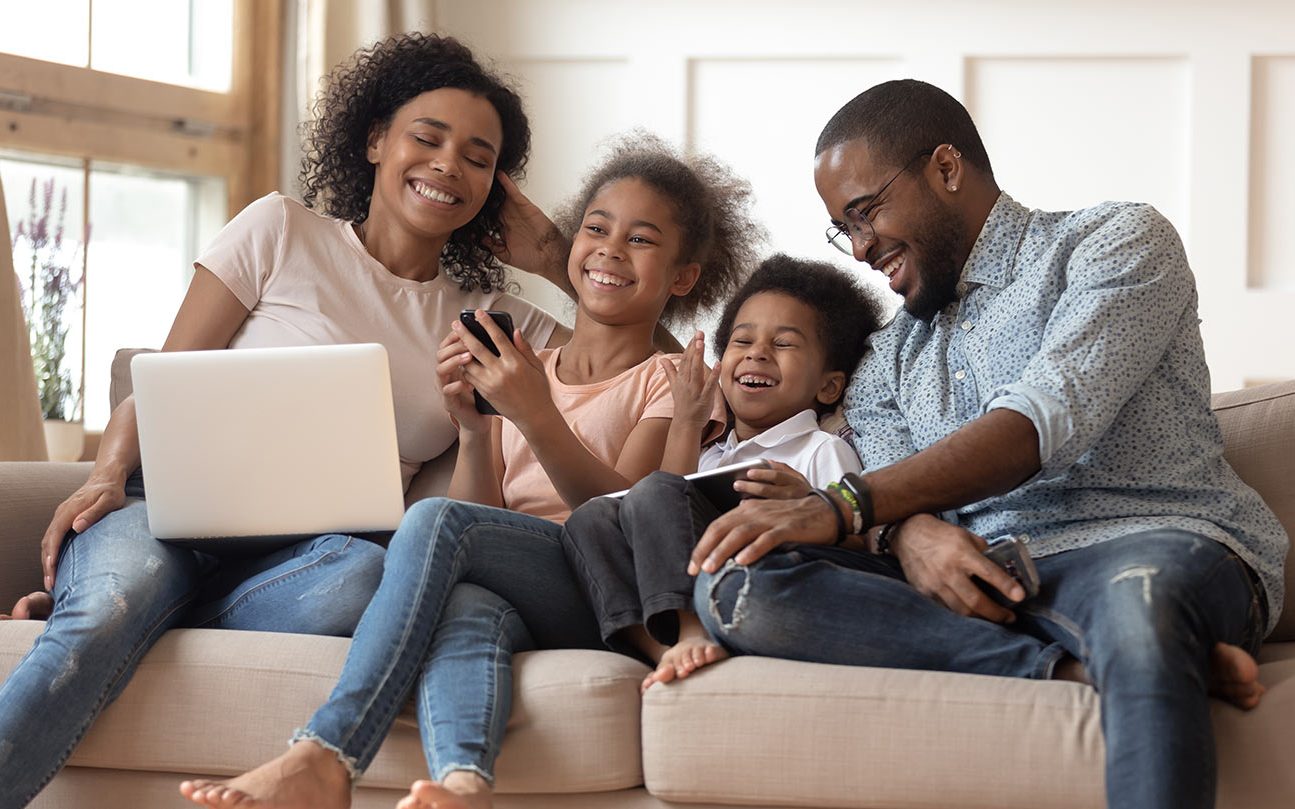 A family sitting on a couch laughing while playing on an iphone