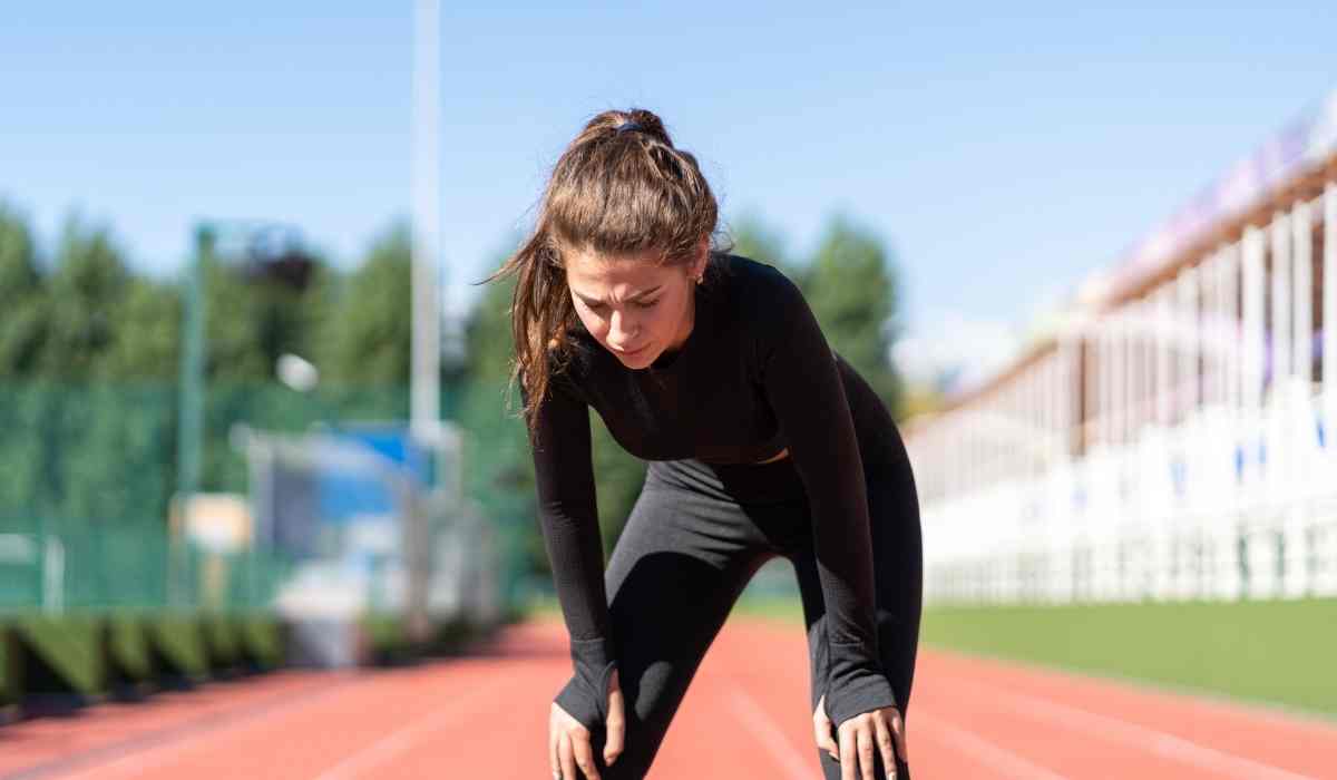 a woman breathing heavily on a track after running