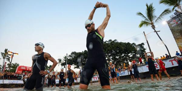 a man fully dressed in a wet-suit as he stretches before the race