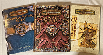 The three source books from Dungeons & Dragons third edition. From left to right is the Dungeon Master's Guide, the Monster Manual, and an Oriental Adventures book.