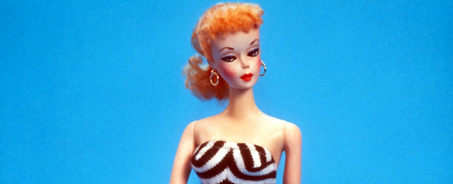 original 1959 Barbie in a striped black and white outfit against a blue background