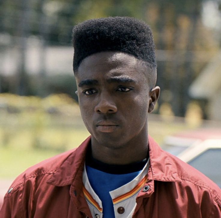 A teenage boy with flat top black hair looks worriedly on.