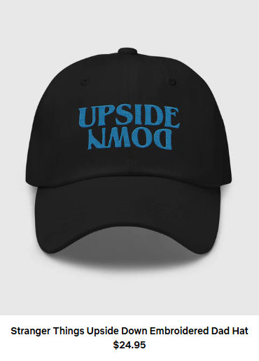A black baseball cap with blue words that say Upside Down with the down actually appearing to be upside down. Words beneath it say Stranger Things Upside Down Embroidered Dad Hat $24.95