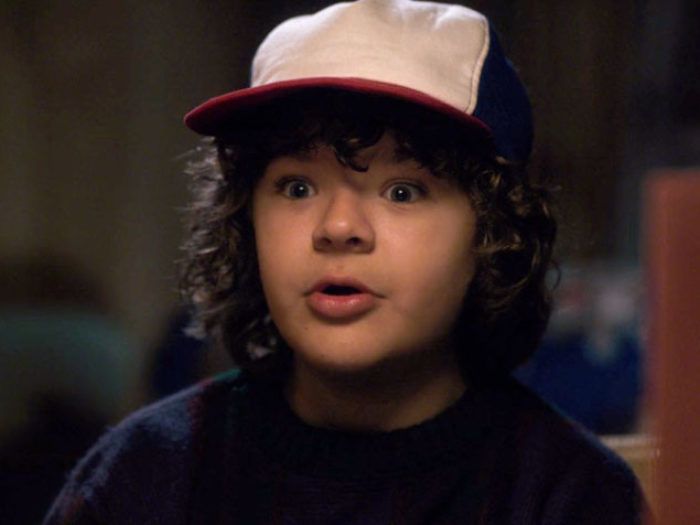 A young boy with curly hair, wide eyes, and a baseball cap.