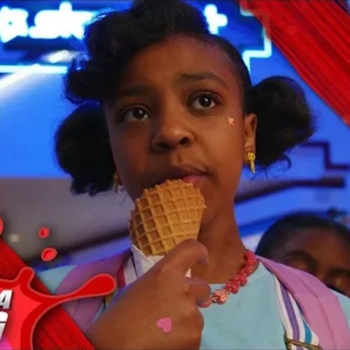 A young girl with curly black hair eats an ice cream cone inside a bright mall.