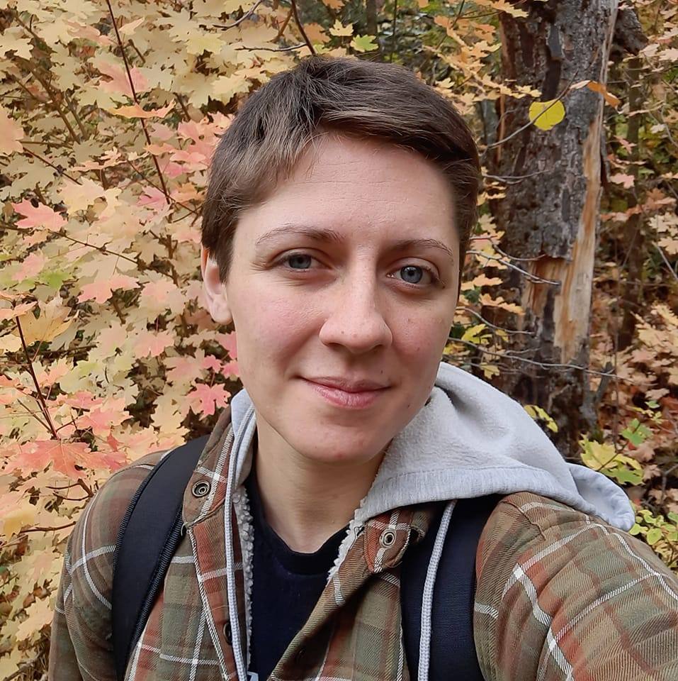 Picture of woman with short brown hair in front of red and yellow leaves