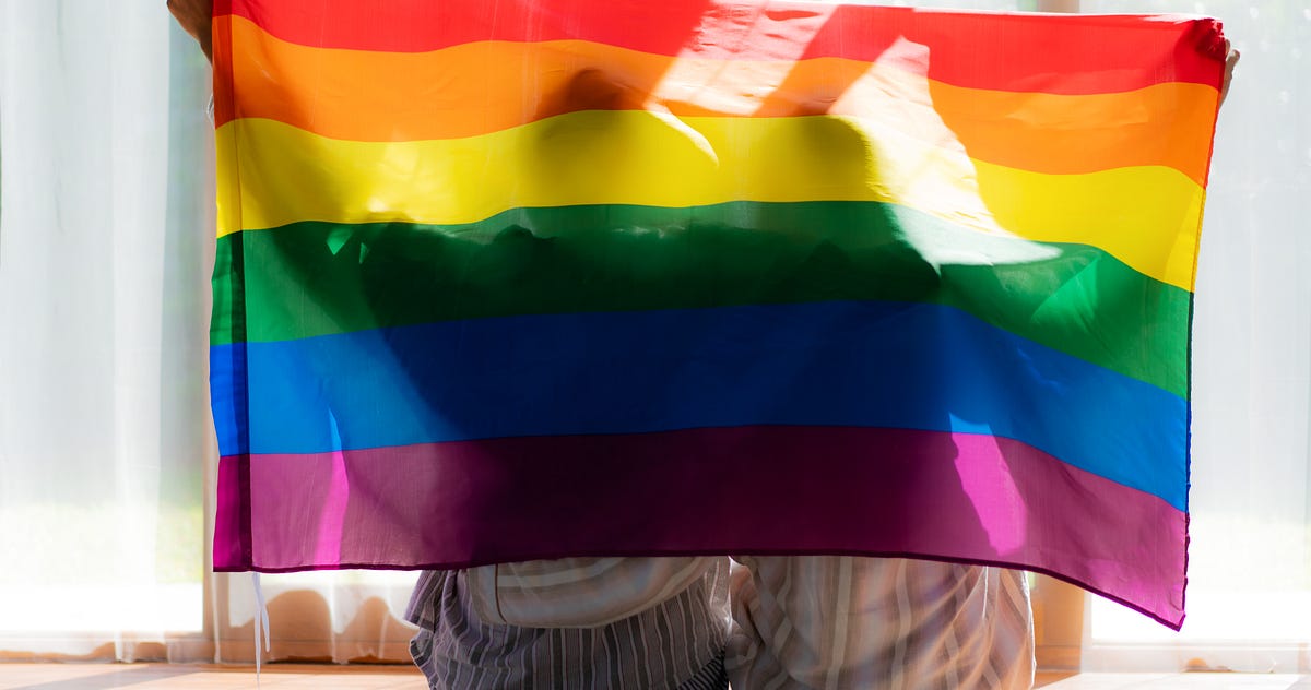 Hands holding up the gay flag infront of themselves
