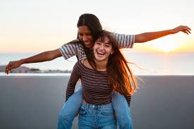 one girl is giving another girl a piggy back ride