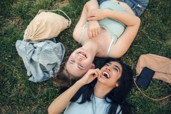 2 women are laying in the grass laughing