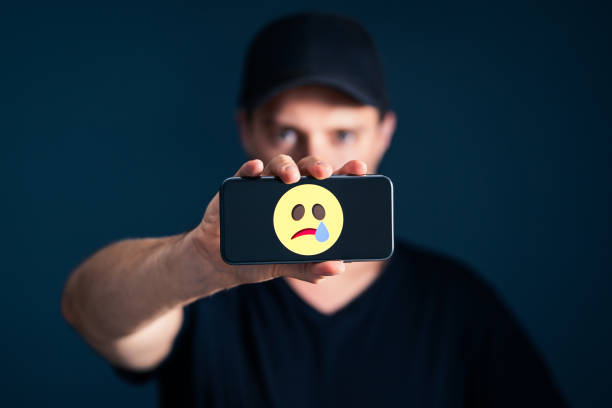 a man holding a phone with an image of a sad emoji