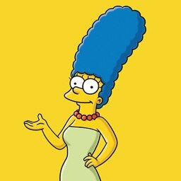 photo of Marge Simpson from the Simpsons. She has yellow skin, purple hair and is wearing a purple dress. She is smiling.