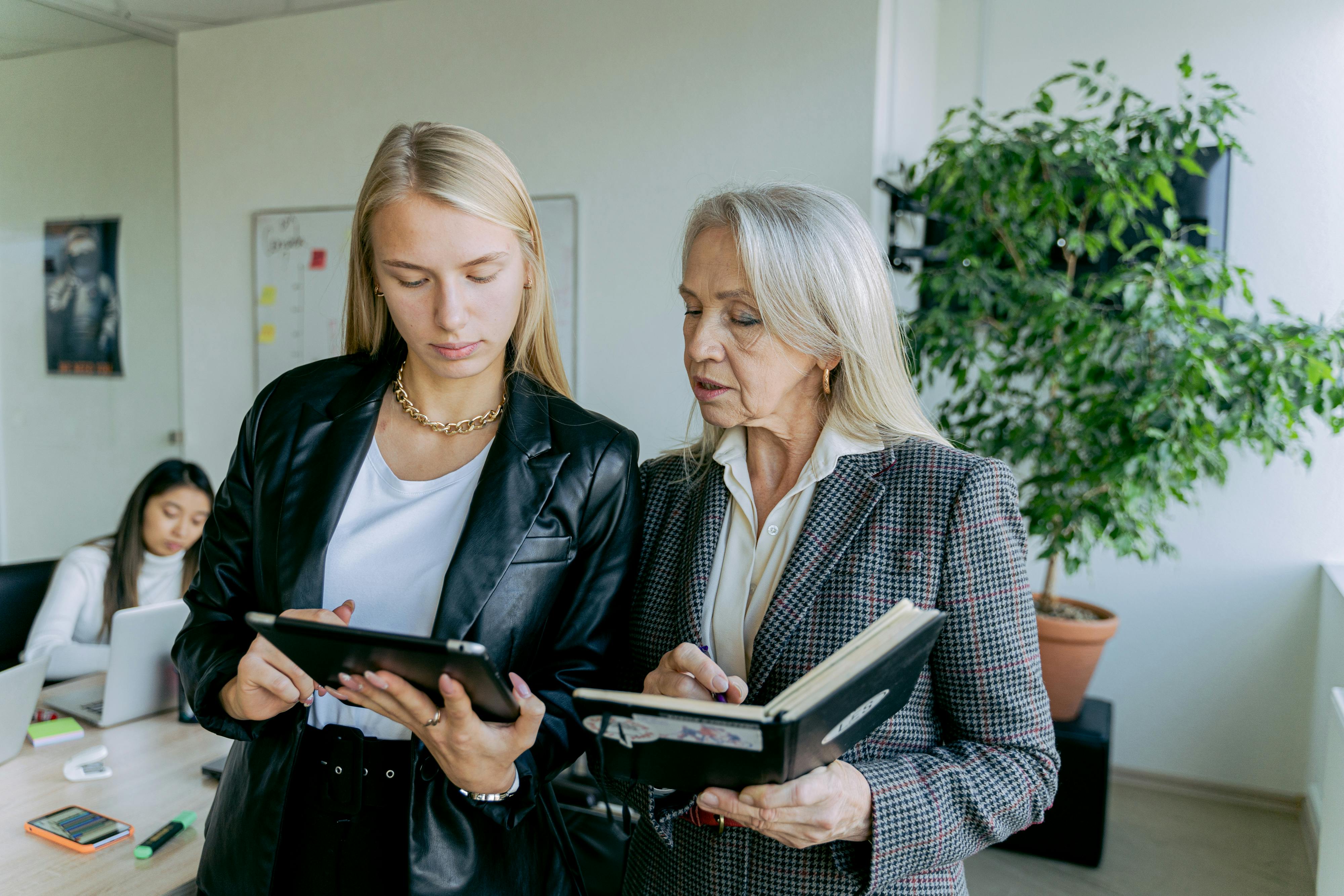 2 Women in Black Suit Jacket Holding Tablet Computer