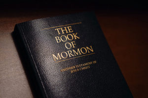 A copy of the Book of Mormon sitting on a wood surface