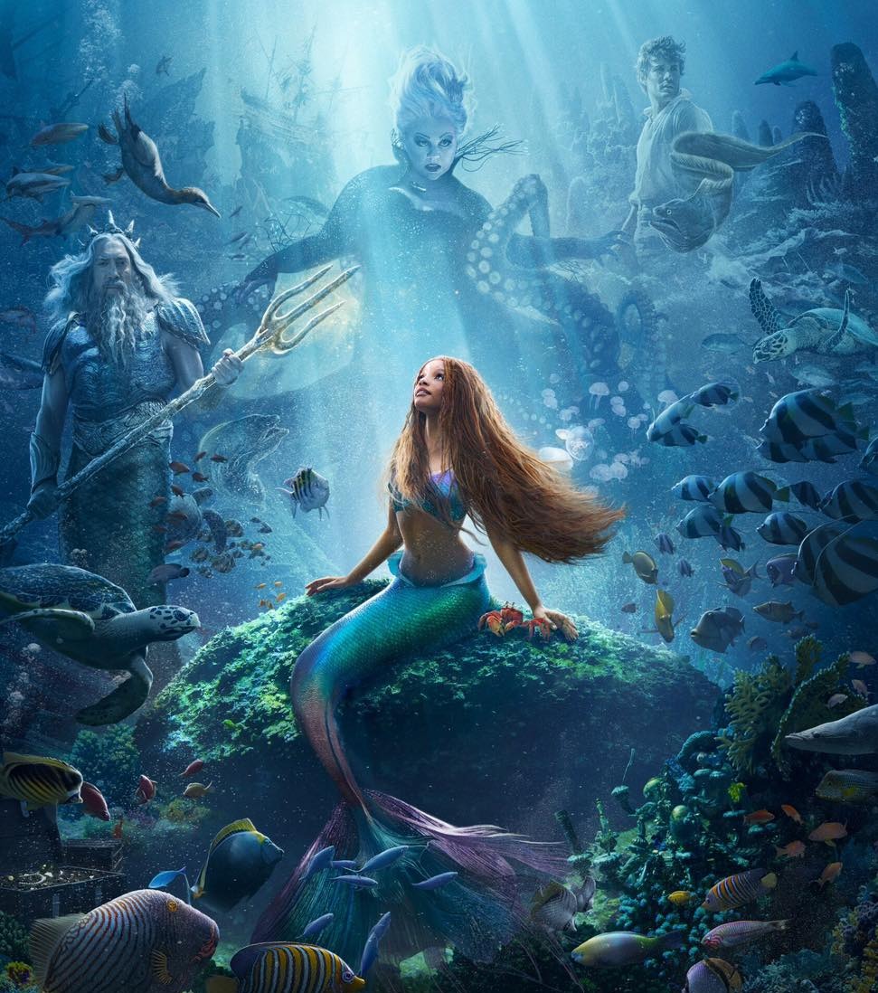 a photo of the 2023 The Little Mermaid marketing poster. It features Ariel on a rock under the sea. In the background, three characters stand over Ariel. On the left, Triton, in the center, Ursula, on the right, Prince Eric. The poster is bordered by colorful CGI fish.