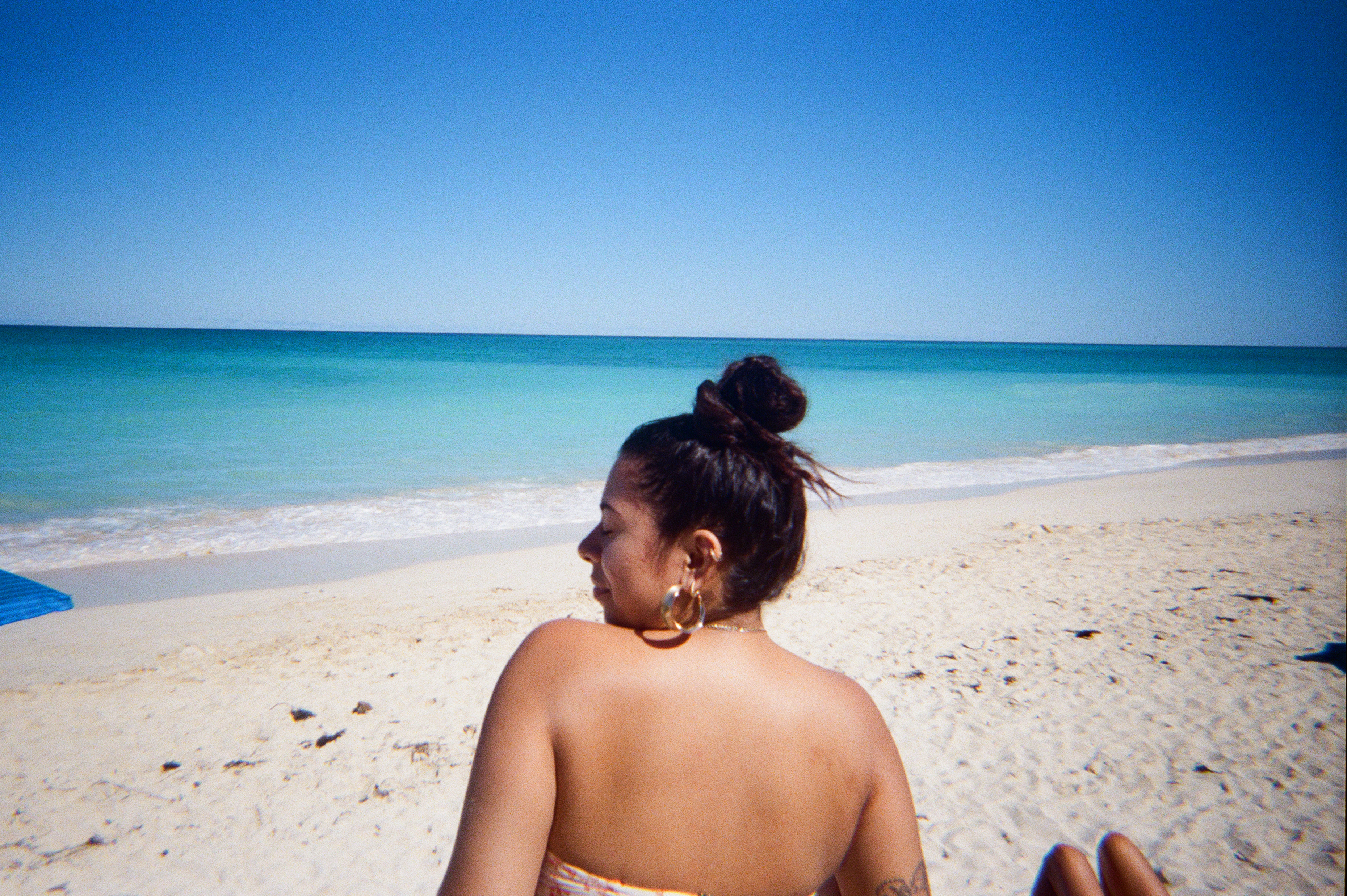 Girl standing in front of Oahu beach, taken from behind.
