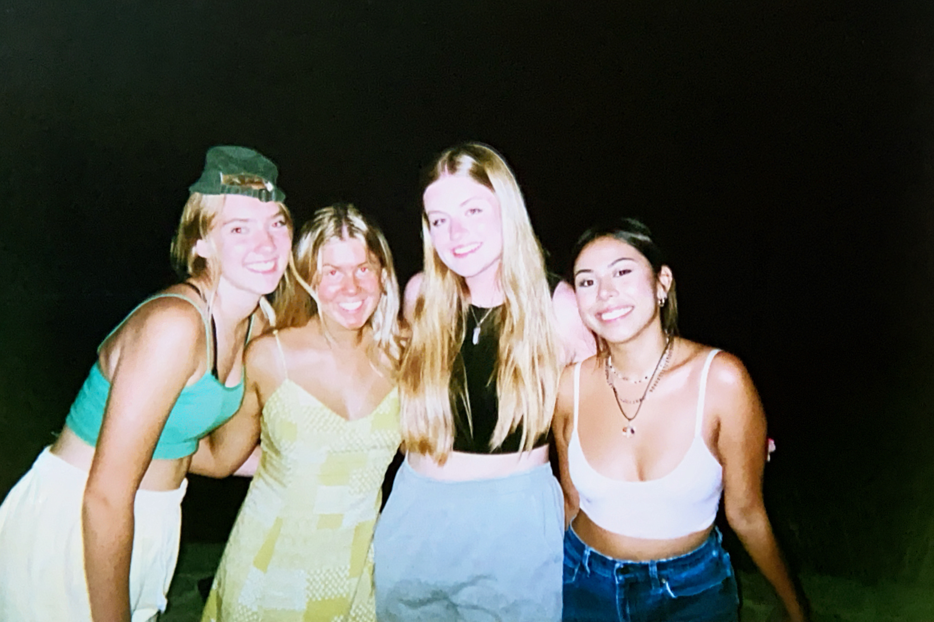 A young woman holding her diploma at high school graduation with one of her sisters on either side of her.