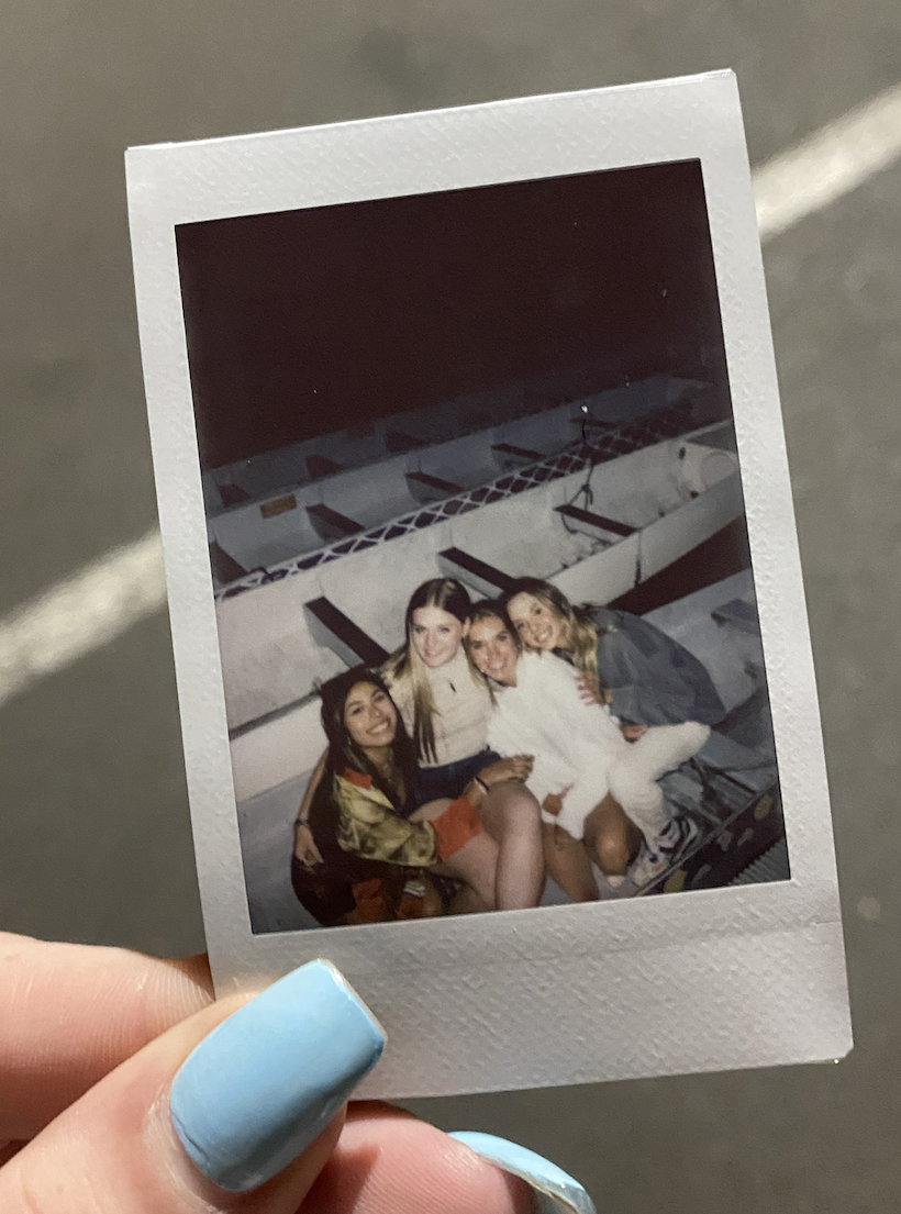 Hand holding a photo of four young women sitting in a dragon boat racing boat in downtown Portland, Oregon waterfront.