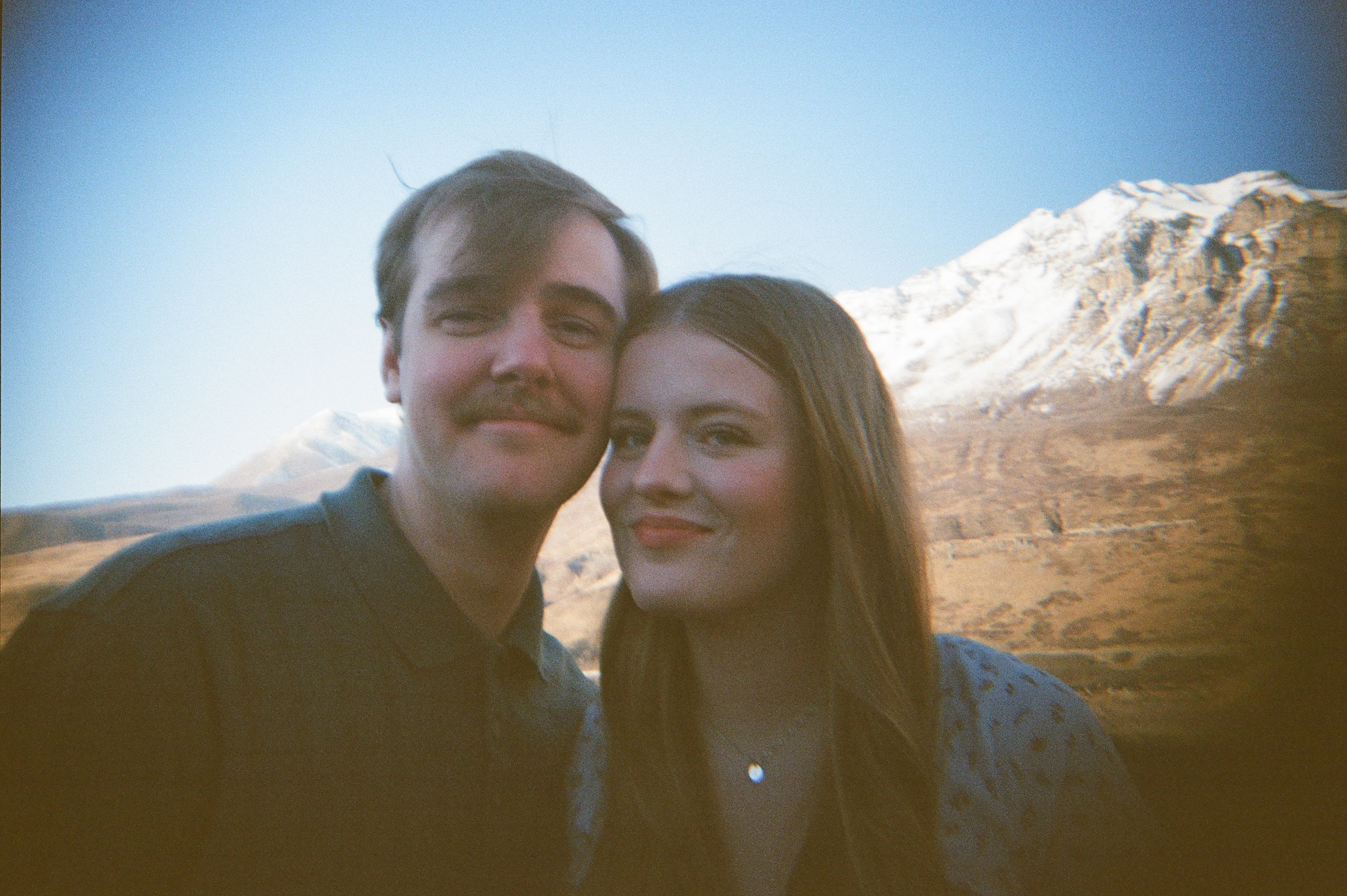 Close-up of a young couple with a mountain background.