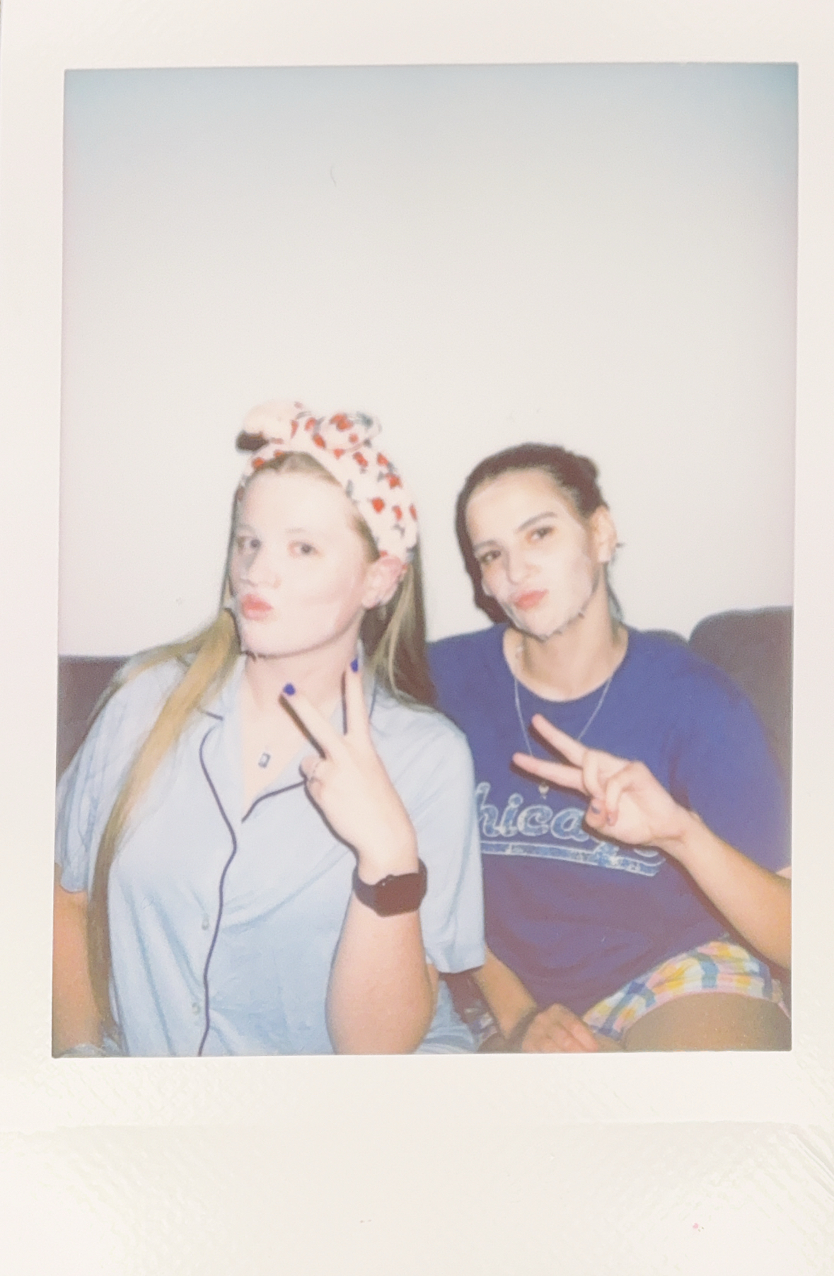 Polaroid of two young women with face masks on.