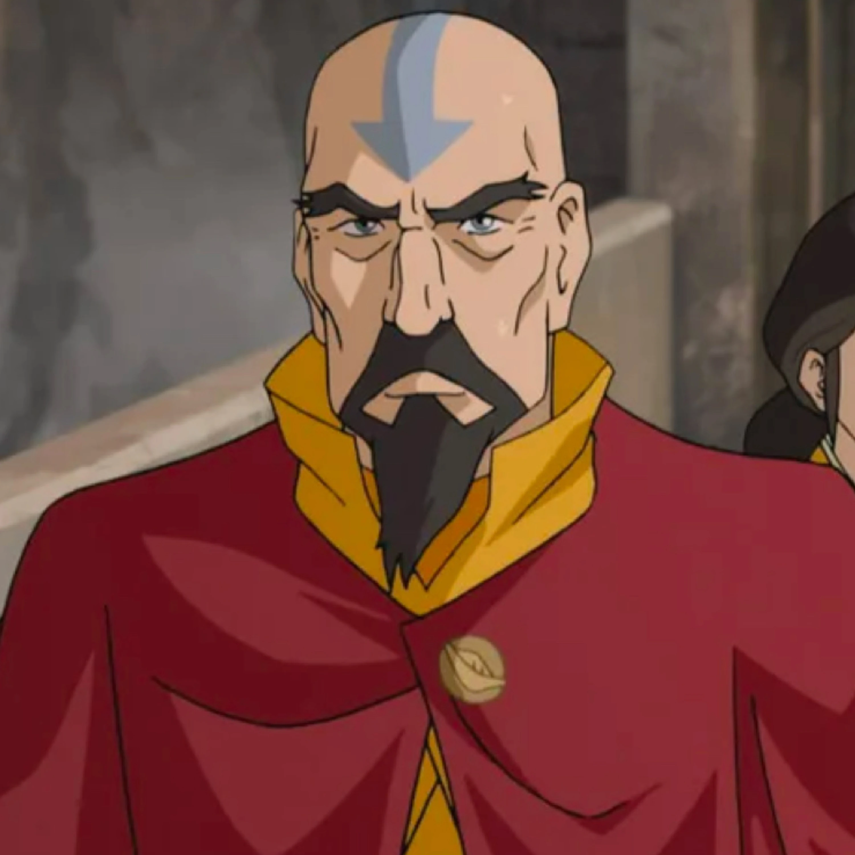 Tenzin, a severe looking man with pronounced eyebrows, a sharp goatee, and an airbending tattoo on his bald head