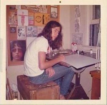 A long haired, teenage Bourdain sketches at a drafting  table.