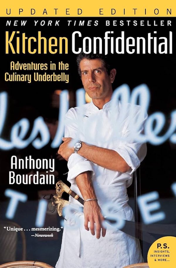 Yellow book cover with Bourdain posing in chef's whites with knife and sharpener in hand.