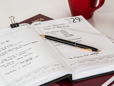 filled out planner with a pen and red coffee mug