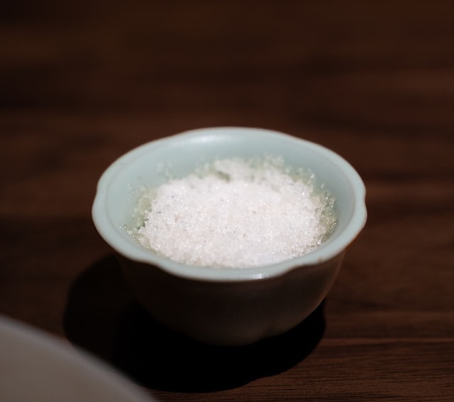 a small blue bowl on a wooden table holding salt